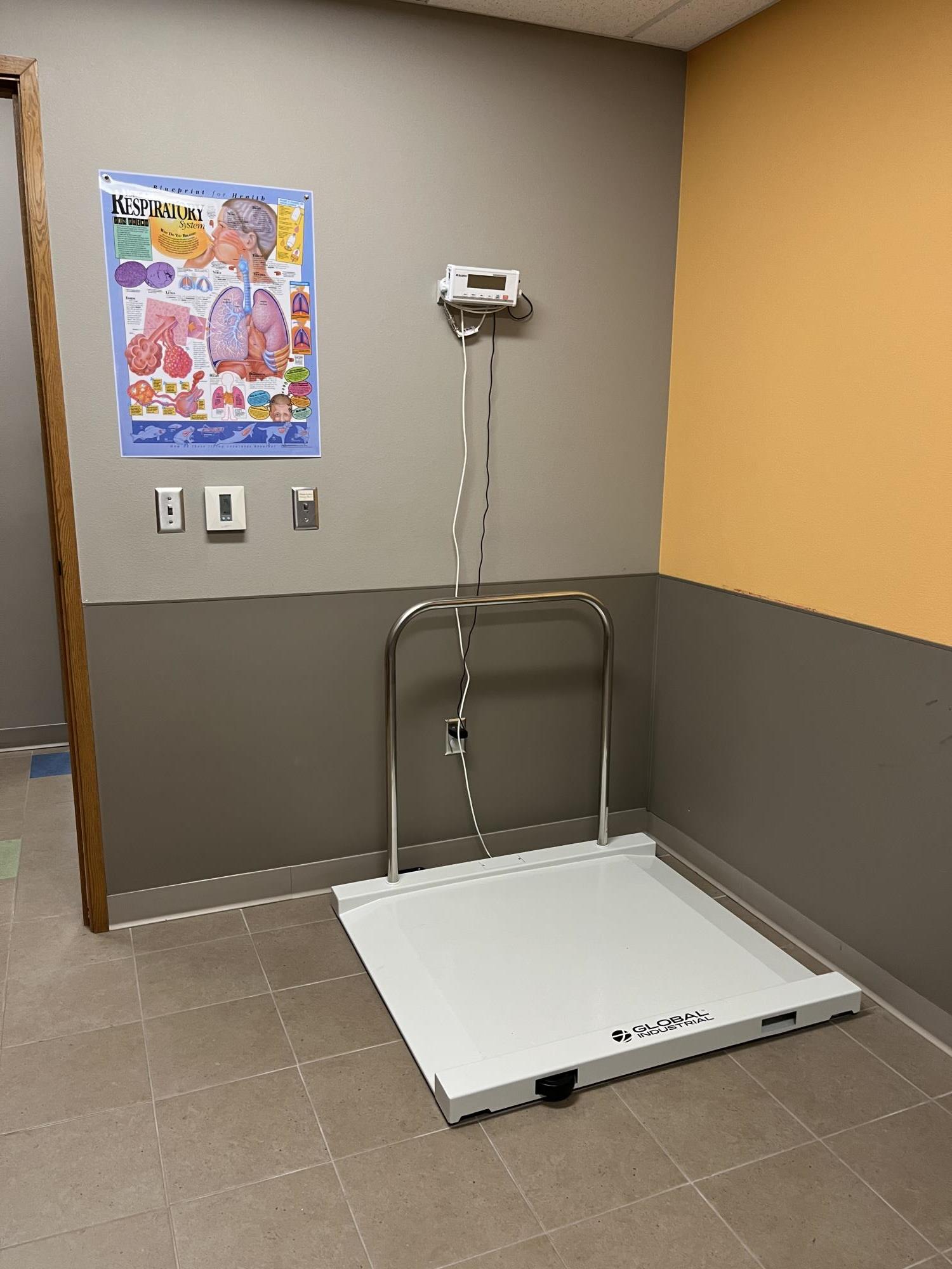 Wheelchair scale next to a wall with the read out attached to the wall