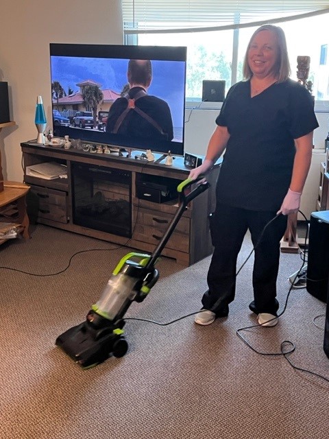 SDHD staff standing, looking at camera, holding a vacuum in one hand and a cord in the other. 