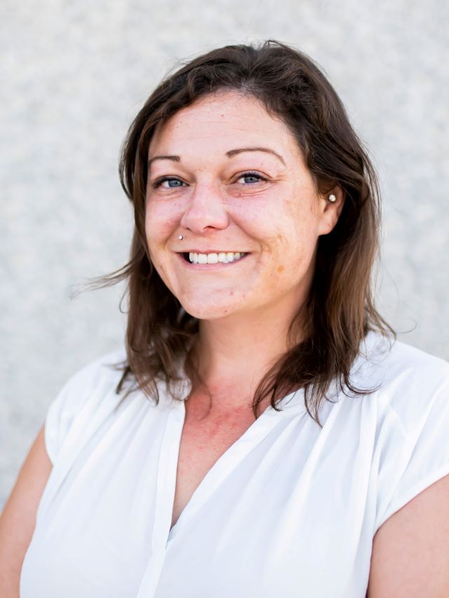 women with dark shoulder length hair, white shirt smiling