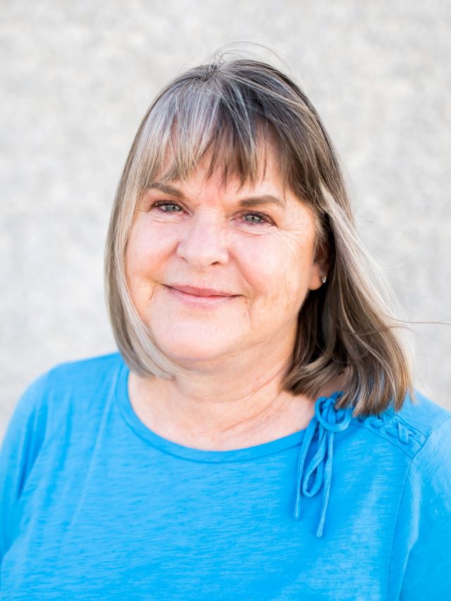 Woman with shoulder length dark hair  and blue shirt smiling