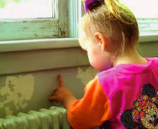 Child touching wall with paint chipping off