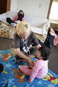 Hopes staff listening to heart beat of a toddler sitting on the floor