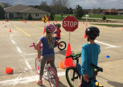 Students on bike at a stop sign and other students riding bike through bike rodeo