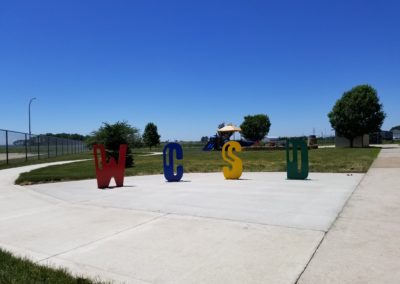 WCSD letters on concrete with playground in the back