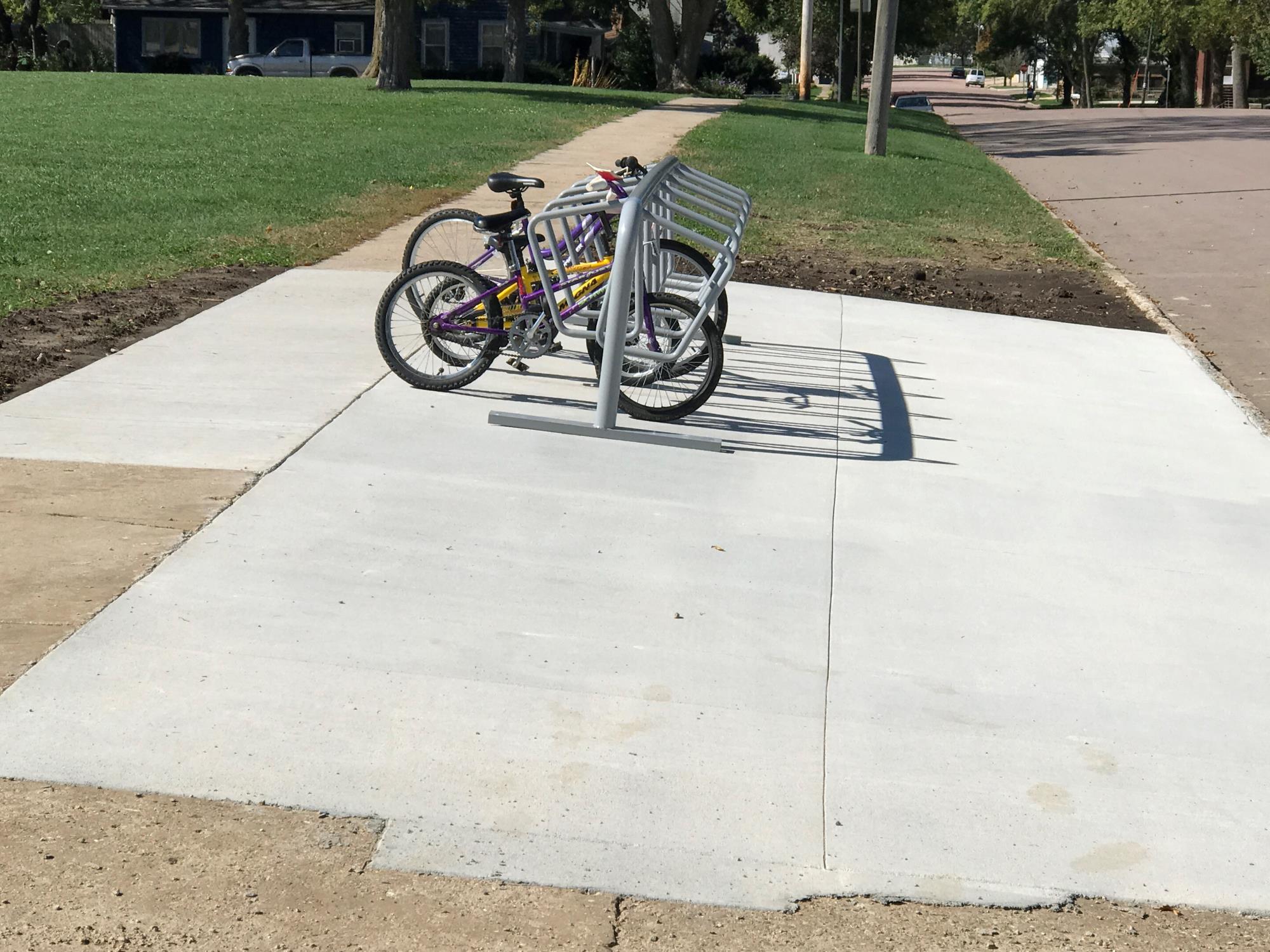 concrete pad with bikes in a bike rack connected to a sidewalk