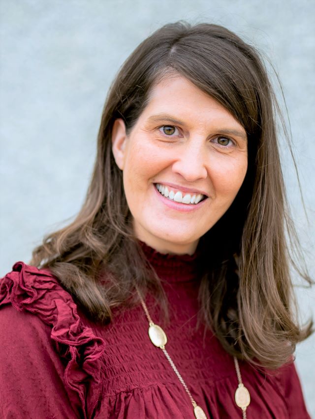 woman with dark long hair and red shirt smiling